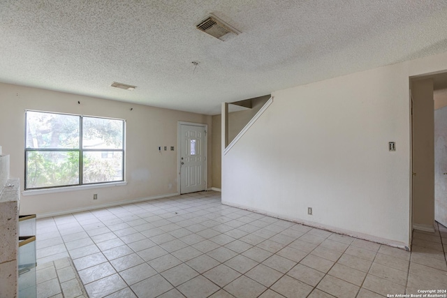 unfurnished room featuring light tile patterned floors and a textured ceiling