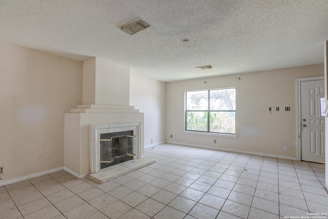 unfurnished living room with a fireplace, light tile patterned floors, and a textured ceiling