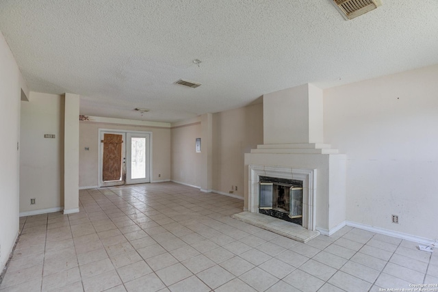 unfurnished living room with a fireplace, light tile patterned floors, and a textured ceiling