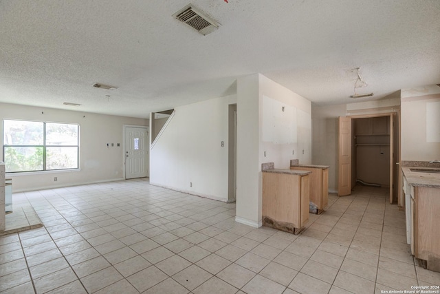 interior space featuring a textured ceiling, light tile patterned floors, and sink