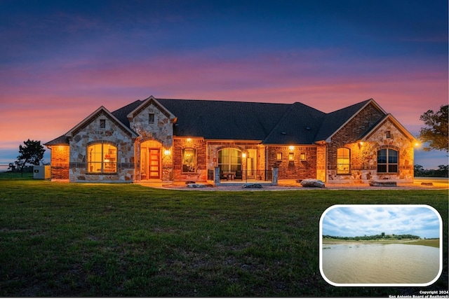 view of front of house featuring stone siding and a lawn