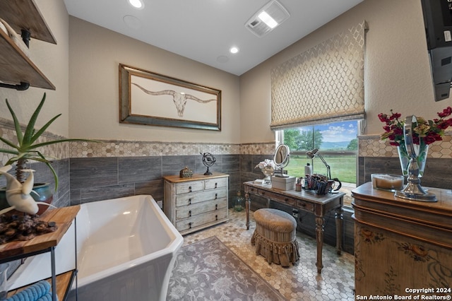 bathroom featuring tile walls, a wainscoted wall, visible vents, a freestanding bath, and tile patterned flooring