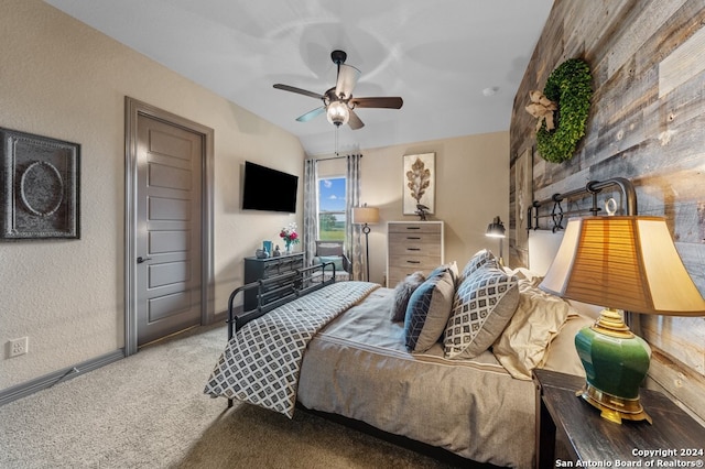 carpeted bedroom featuring a textured wall and a ceiling fan