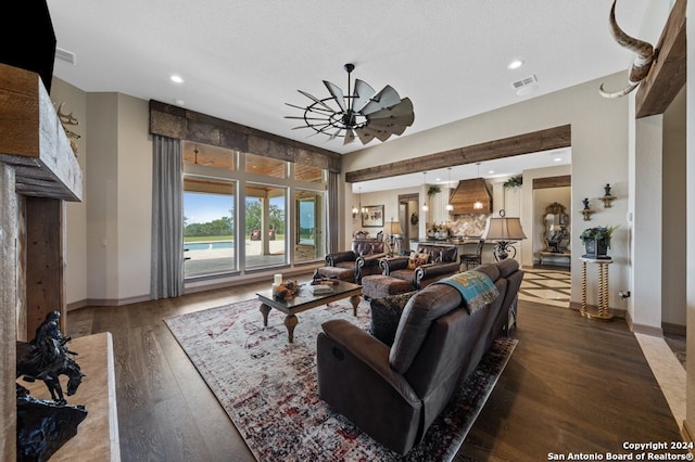 living room with a textured ceiling, dark wood-type flooring, and ceiling fan