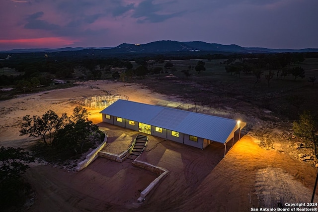 aerial view at dusk featuring a mountain view and a rural view
