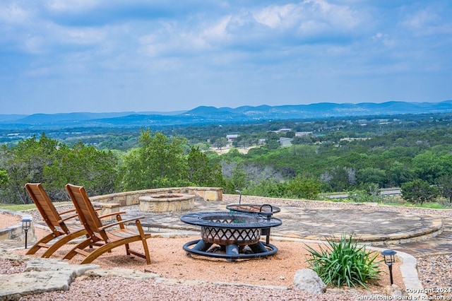 view of patio / terrace with a fire pit, a forest view, and a mountain view
