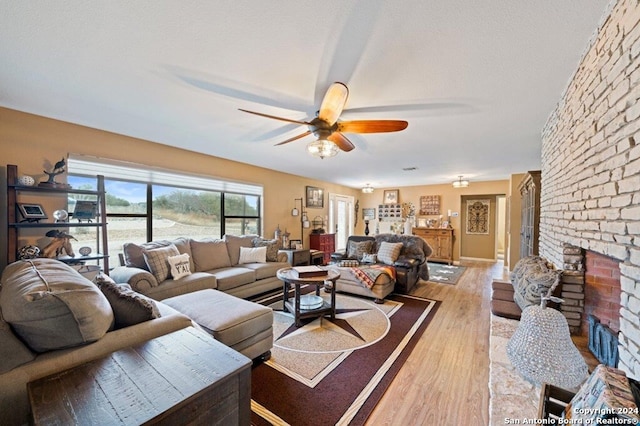 living room featuring a fireplace, a textured ceiling, wood-type flooring, and ceiling fan