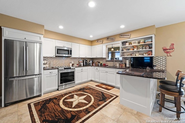 kitchen featuring stainless steel appliances, dark stone counters, kitchen peninsula, and tasteful backsplash