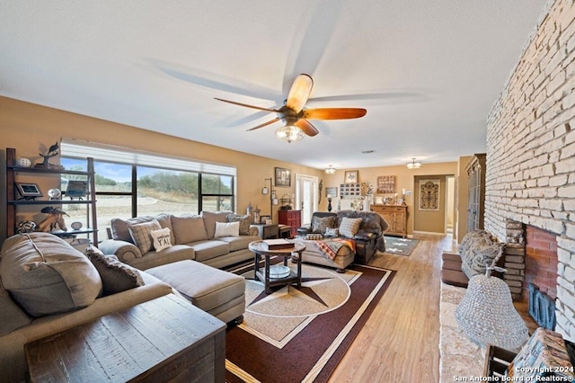 living area featuring a textured ceiling, a fireplace, wood finished floors, and a ceiling fan