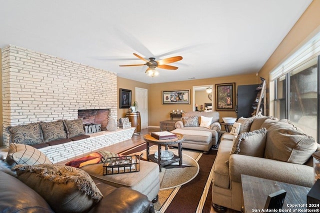 living room with ceiling fan, a fireplace, and brick wall