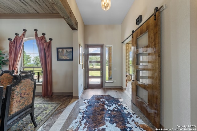 foyer featuring baseboards, a barn door, and wood finished floors