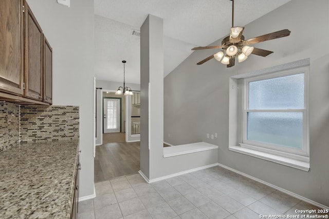 interior space featuring plenty of natural light, light tile patterned flooring, ceiling fan with notable chandelier, and vaulted ceiling