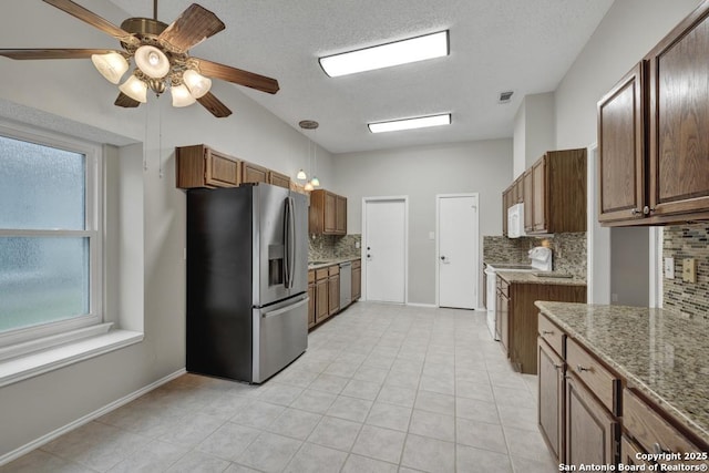 kitchen with decorative backsplash, ceiling fan, light stone countertops, and appliances with stainless steel finishes