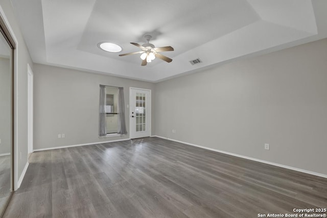 spare room featuring hardwood / wood-style floors, ceiling fan, and a raised ceiling