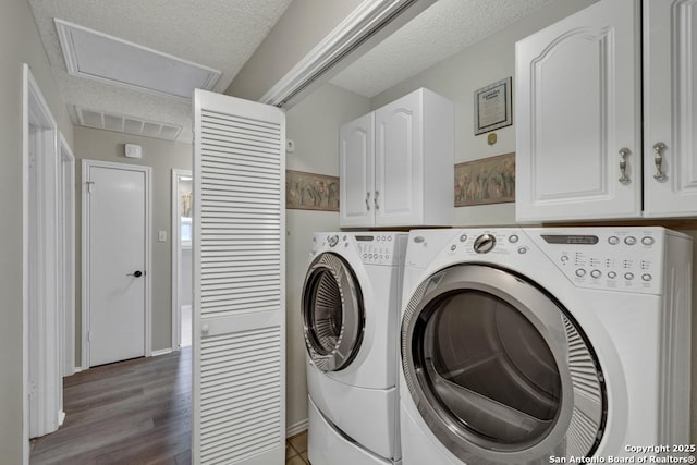 clothes washing area featuring cabinets, hardwood / wood-style floors, washer and dryer, and a textured ceiling