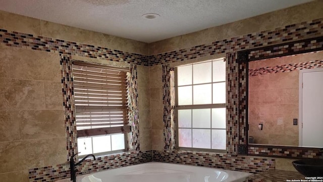 bathroom featuring sink, tile walls, a textured ceiling, and a bathtub