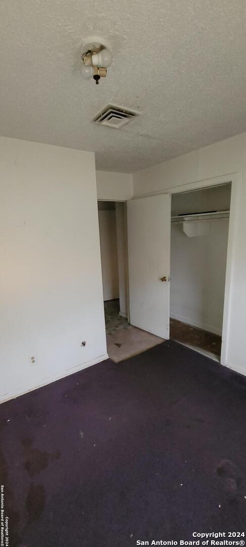 unfurnished room with dark carpet and a textured ceiling