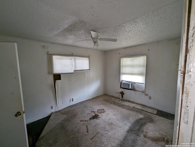 spare room with carpet flooring, ceiling fan, cooling unit, and a textured ceiling