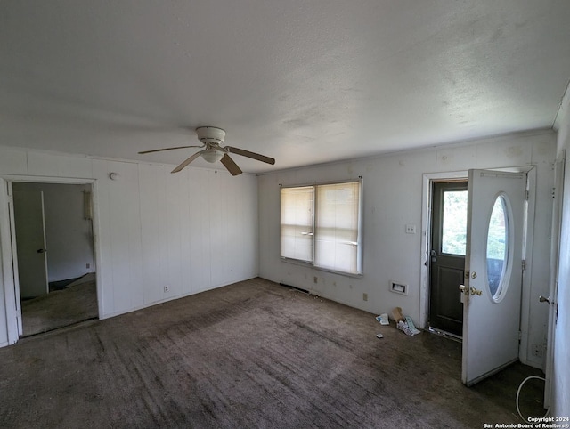 interior space with a textured ceiling, dark carpet, and ceiling fan