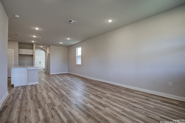 unfurnished living room with sink and light hardwood / wood-style floors