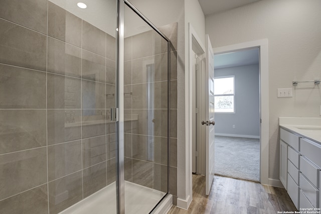 bathroom featuring hardwood / wood-style flooring, a shower with door, and vanity