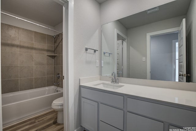 full bathroom featuring toilet, tiled shower / bath, wood-type flooring, and vanity