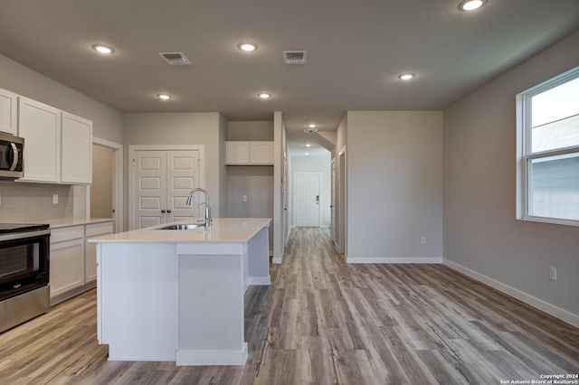 kitchen with stainless steel appliances, a center island with sink, and white cabinets