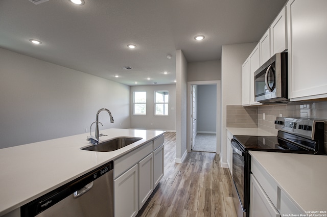 kitchen featuring appliances with stainless steel finishes, white cabinetry, tasteful backsplash, and sink