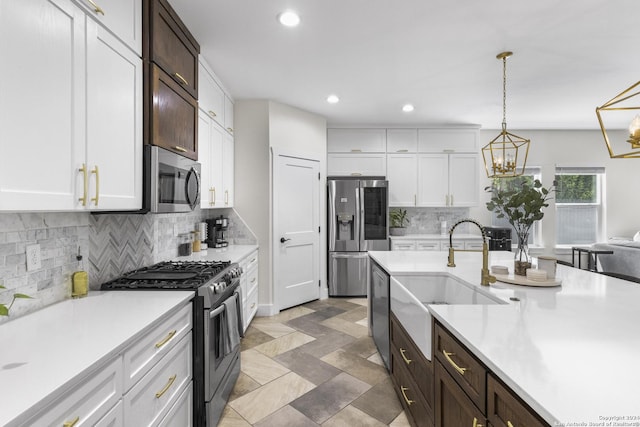 kitchen featuring sink, stainless steel appliances, backsplash, pendant lighting, and white cabinets