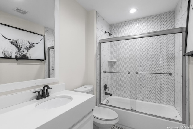 full bathroom with combined bath / shower with glass door, vanity, and toilet