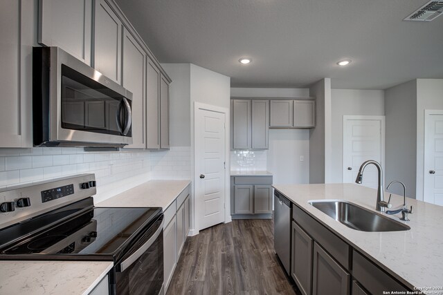 kitchen with appliances with stainless steel finishes, gray cabinets, tasteful backsplash, and sink