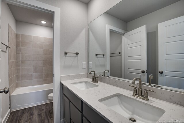 full bathroom with wood-type flooring, vanity, toilet, and tiled shower / bath