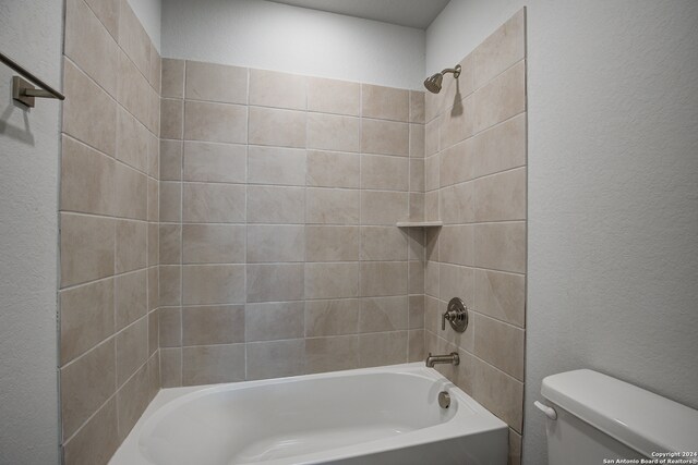 bathroom with toilet and tiled shower / bath