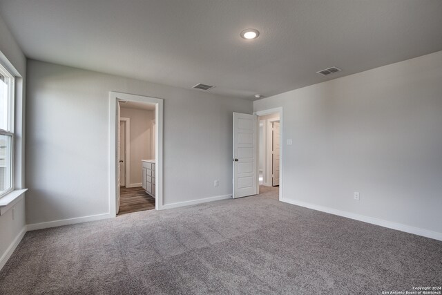 unfurnished bedroom featuring ensuite bath and carpet