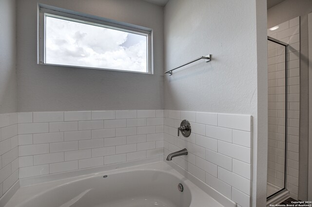 bathroom featuring plenty of natural light and shower with separate bathtub