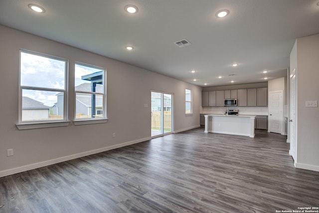 unfurnished living room with dark hardwood / wood-style floors and a healthy amount of sunlight