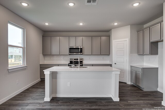 kitchen featuring gray cabinetry, a center island with sink, and stainless steel appliances