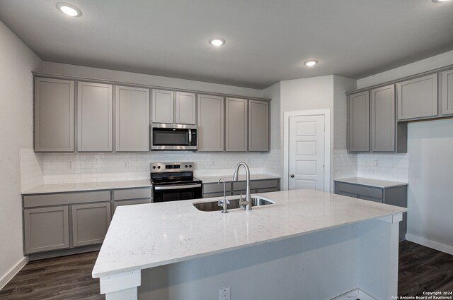 kitchen with a center island with sink, gray cabinets, sink, and appliances with stainless steel finishes