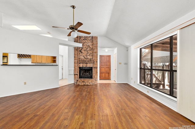 unfurnished living room with brick wall, ceiling fan, hardwood / wood-style flooring, and a fireplace