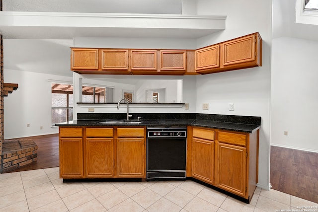 kitchen with dark stone counters, kitchen peninsula, sink, light tile flooring, and dishwasher