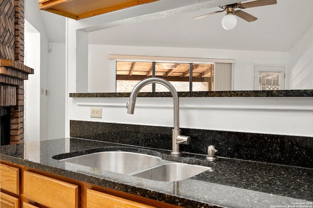 kitchen with ceiling fan, sink, and dark stone countertops