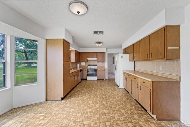 kitchen with tasteful backsplash, sink, a textured ceiling, and white appliances