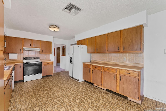 kitchen with sink, backsplash, a textured ceiling, and white appliances