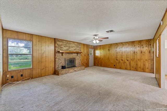 unfurnished living room featuring a fireplace, carpet floors, a textured ceiling, and wood walls