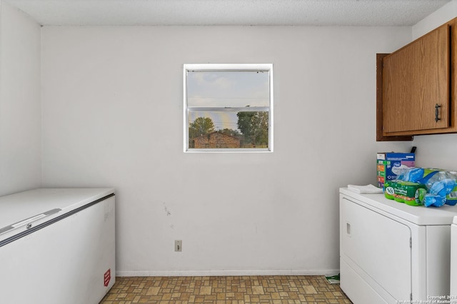 laundry room featuring cabinets, washer / clothes dryer, and a textured ceiling