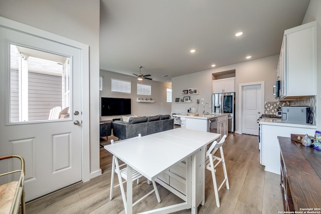 dining space featuring light wood-type flooring, ceiling fan, and sink