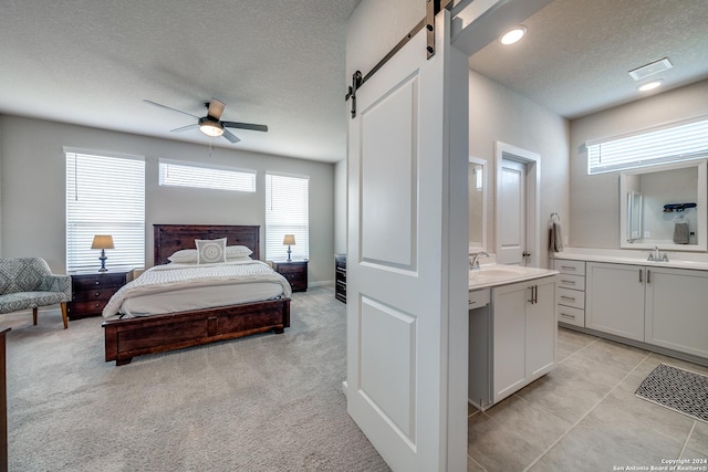 carpeted bedroom featuring sink, a barn door, ceiling fan, and connected bathroom