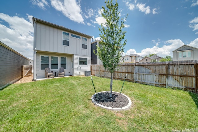 back of property with central AC and a lawn