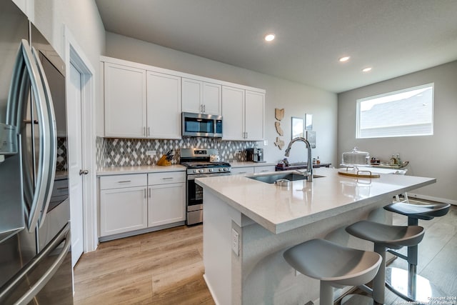 kitchen featuring white cabinets, stainless steel appliances, a center island with sink, and sink