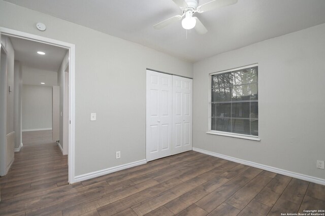 unfurnished bedroom with ceiling fan, dark wood-type flooring, and a closet